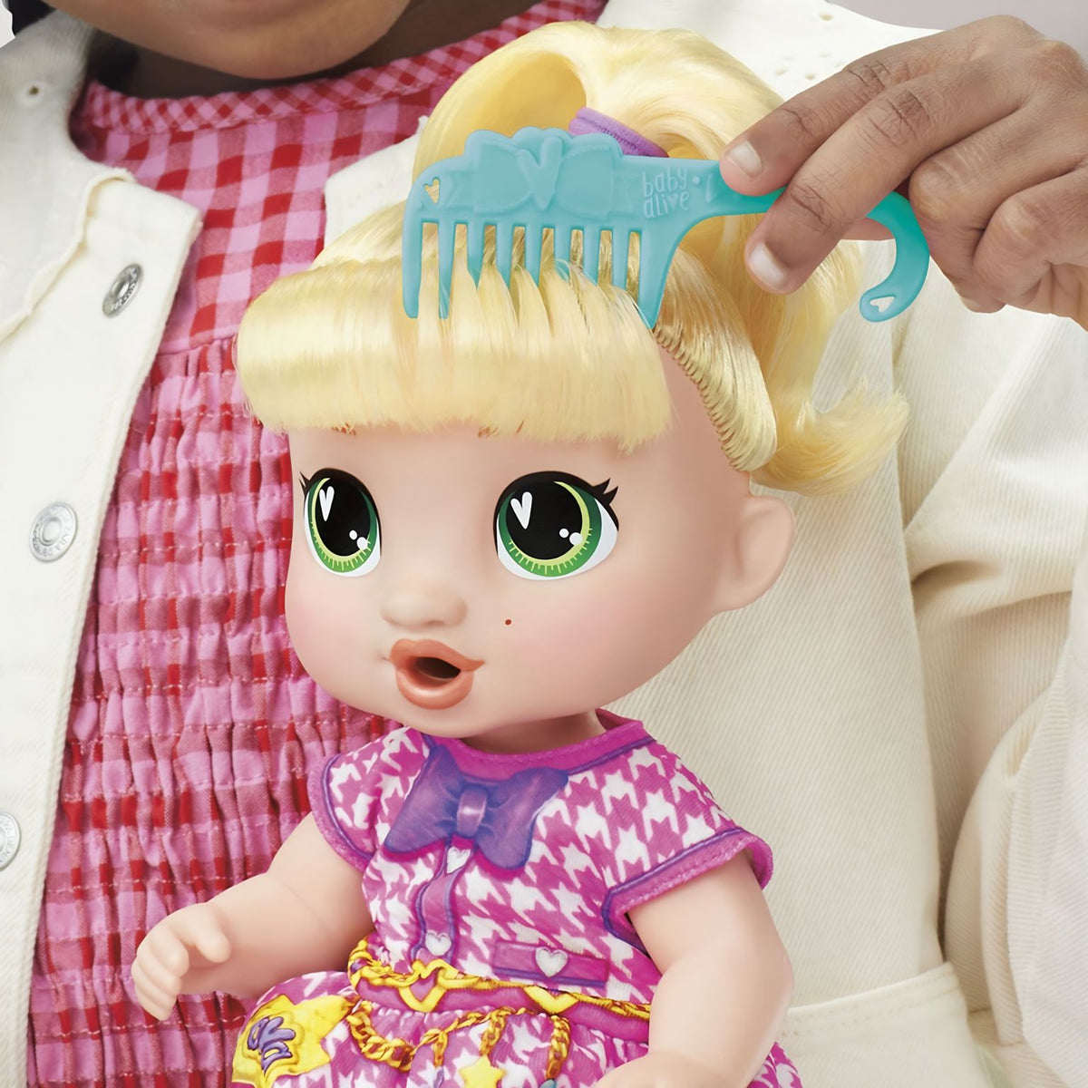 Criança a pentear o cabelo louro da Baby Alive LaLa GooGoo com o pente azul