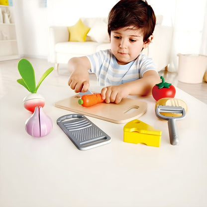 Child playing with Hape children's cooking set with chopping board, vegetables, and utensils