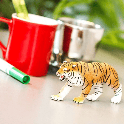 Figura de borracha Tigre de Bengala numa mesa junto a canecas